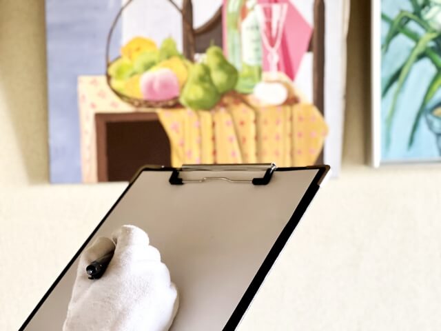 絵画を前にファイルにメモする手