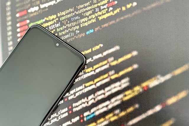 スマートフォンの裏側にプログラミングコードが映っている