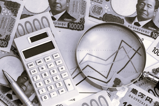 電卓・紙幣・虫眼鏡が映ったモノクロ写真