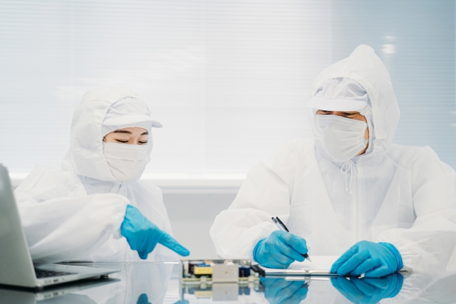 クリーンルームで作業するクリーンスーツ姿の二人