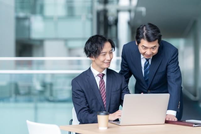 カフェでPCをのぞき込む若手社員とベテラン社員