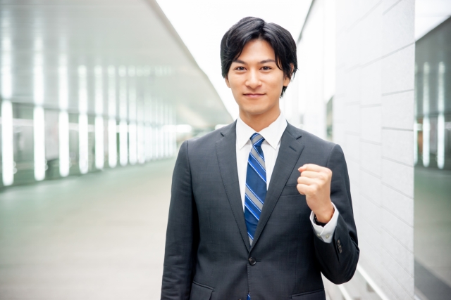 若い男性サラリーマンがこぶしを握ってガッツポーズをしている
