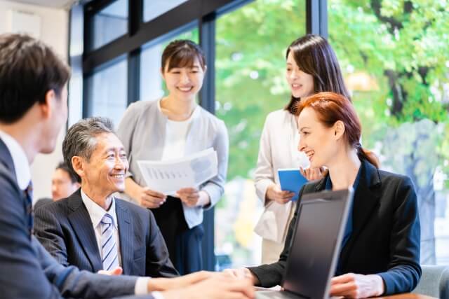 窓際の席でミーティングをしている男女社員