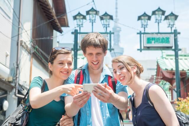 スマホを見て相談している海外旅行客3人