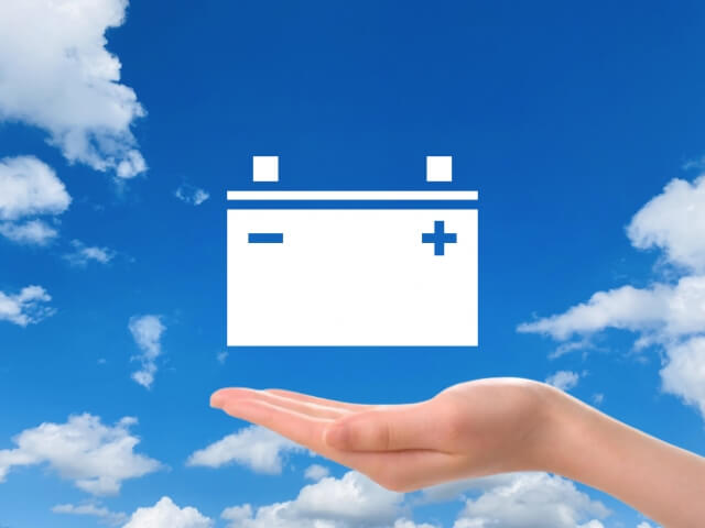 青空を背景にバッテリーのイラストを手が支えている