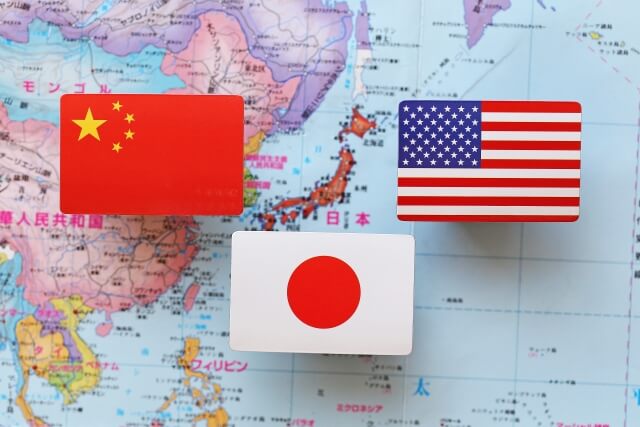 世界地図の上にある中国国旗、アメリカ国旗、日本国旗