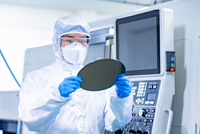 半導体工場内でウエハ状態を確認する防塵服姿の人
