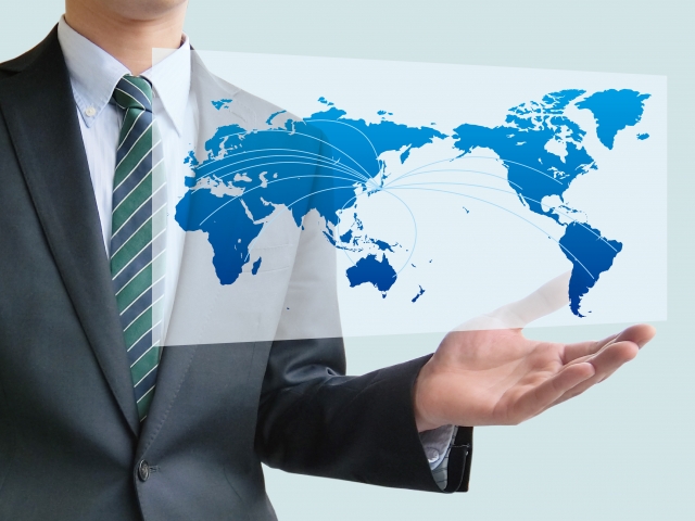 スーツ姿の男性が世界地図の手に浮かべている
